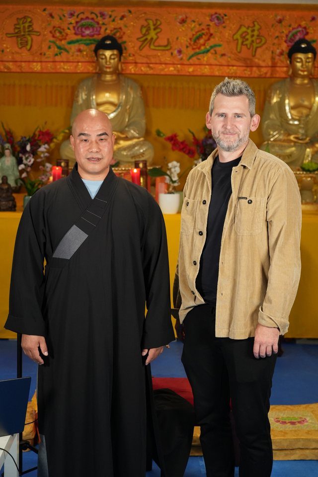 Michael Plank mit einem Gast im Mönchsgewand vor goldenen Statuen